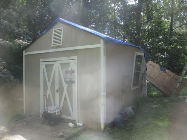 Storage shed with tarped roof after storm damage